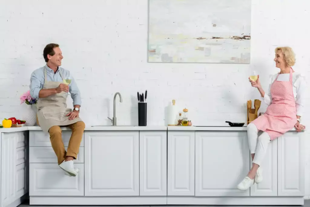Happy couple in a white kitchen, a classic example of where to buy kitchen cabinets for a homey feel