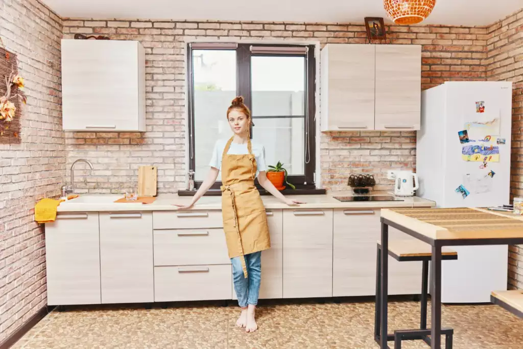 Rustic kitchen with light wood cabinets and a woman in an apron, hinting where to buy kitchen cabinets with charm.