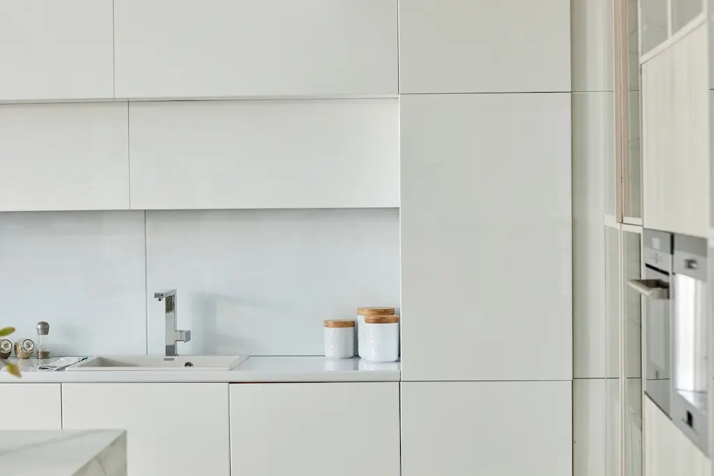 Sleek, all-white minimalist kitchen cabinets that make use of vertical storage with simple decor - kitchen renovation ideas Vancouver.